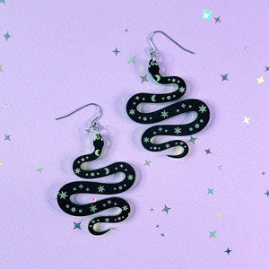 Acrylic earrings shaped like a snake with moon and star details.